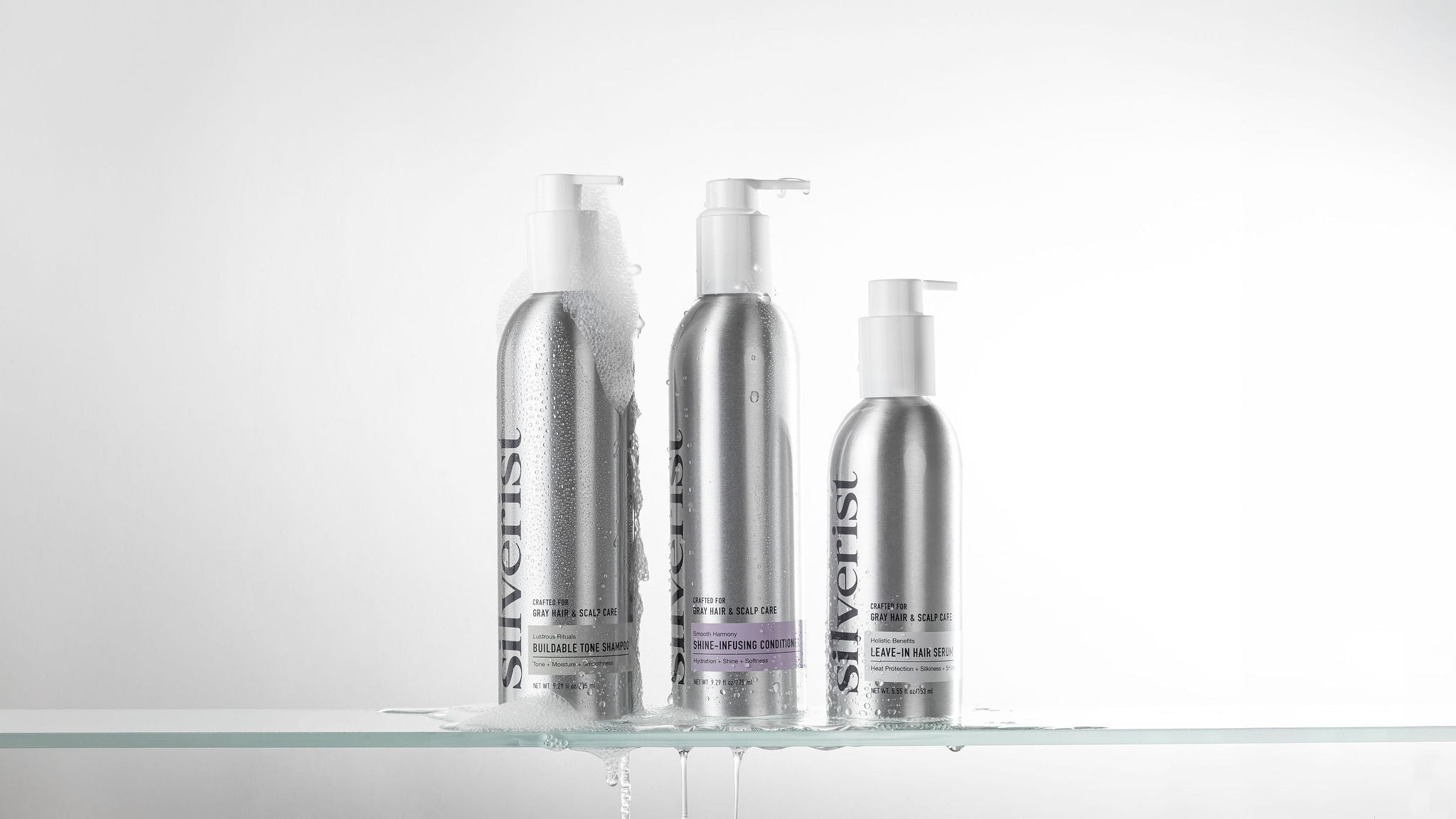 Three silver pump bottles from the brand Silverist, arranged on a clear glass shelf against a white background.